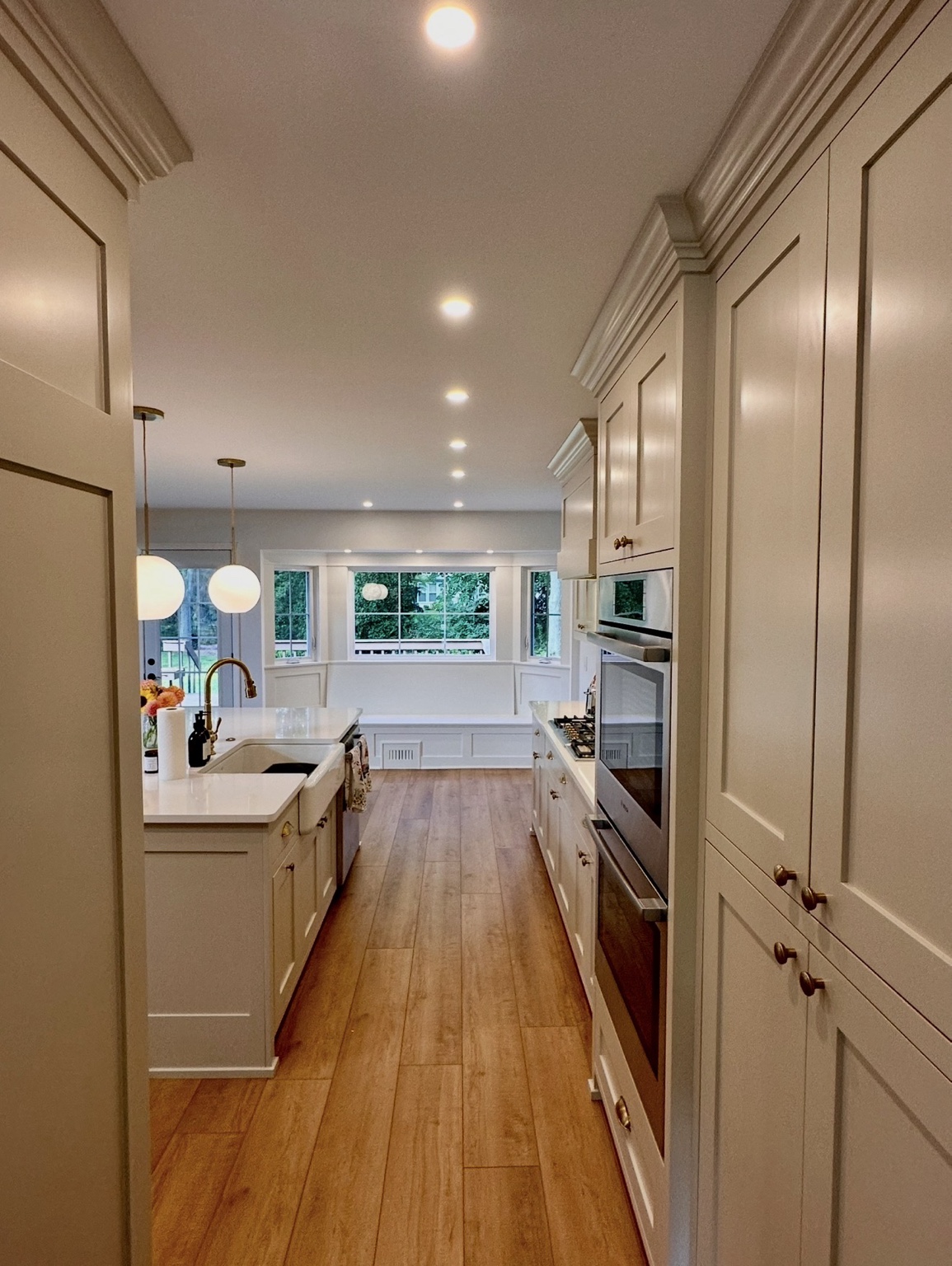 Long view through a custom kitchen toward a bright window seat