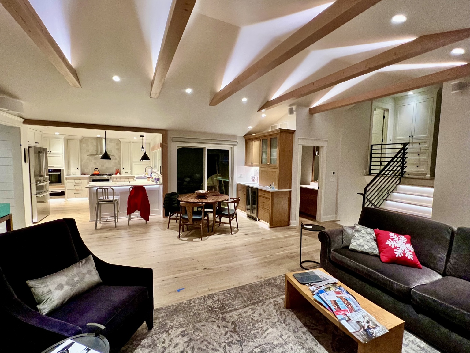 Open living area with exposed timber beams flowing into a bright custom kitchen